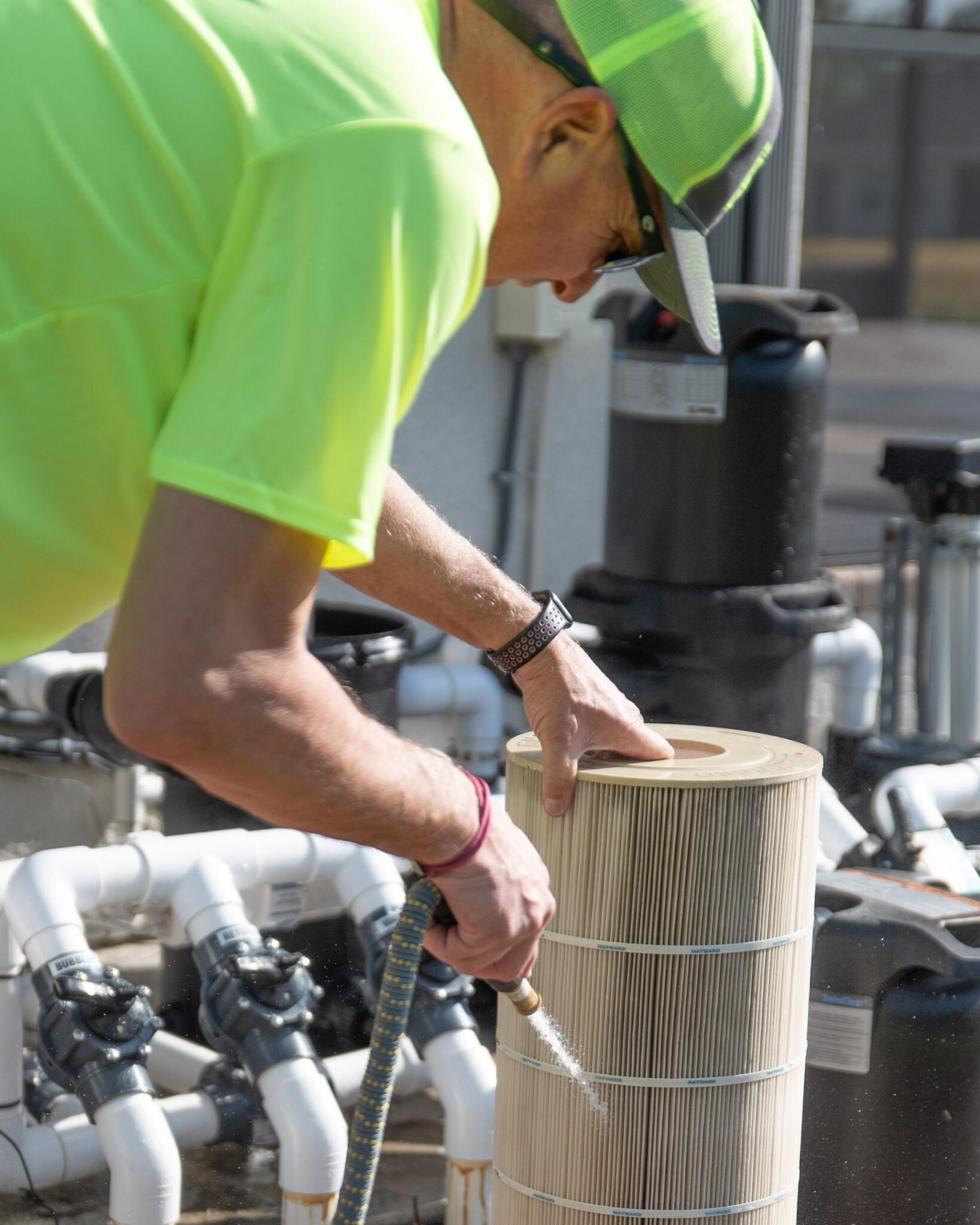 Pool doctor technician cleaning a pool filter with a water hose.